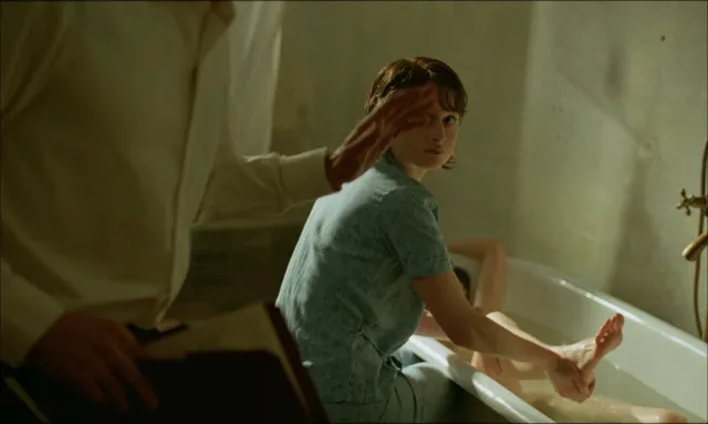 Felicity Jones turning in a bathtub in a screen scene.