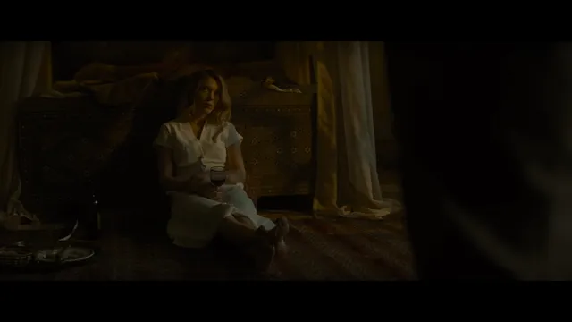 Léa Seydoux sitting on a floor in a dimly lit scene.