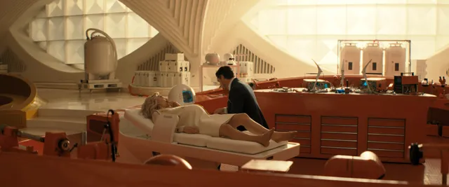Vanessa Kirby a reclining screen scene on a sofa in a bright room.
