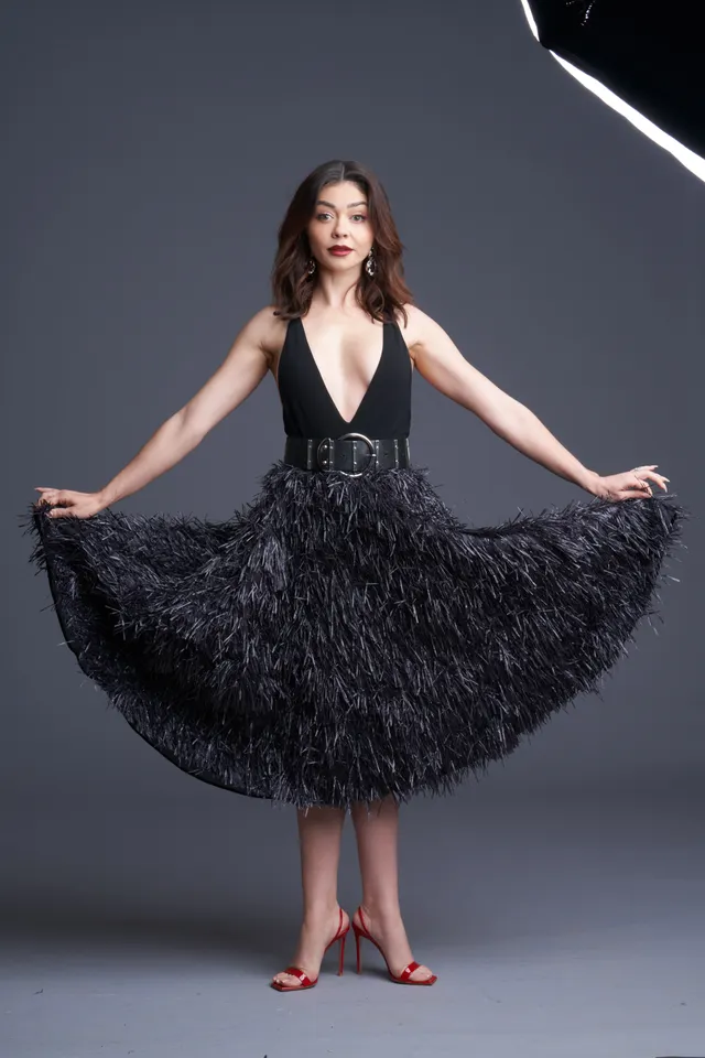 Sarah Hyland posing for a studio portrait in a black feathered dress.
