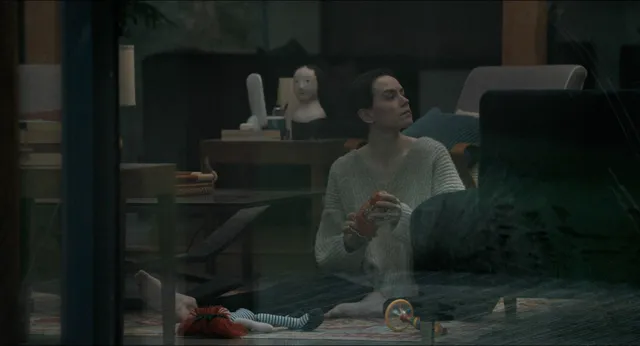 Daisy Ridley sitting beside a bed in a screen scene.