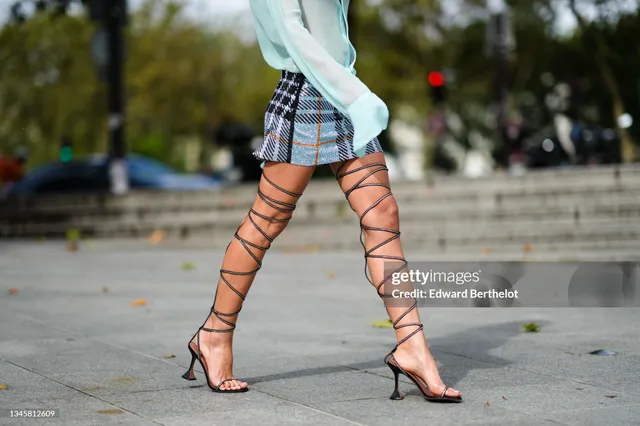 Bruna Marquezine shown walking outdoors in a short checked skirt and lace-up heels.