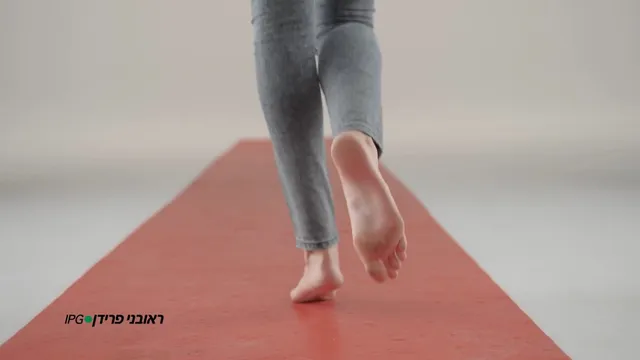 Gal Gadot walking barefoot on a red exercise mat.