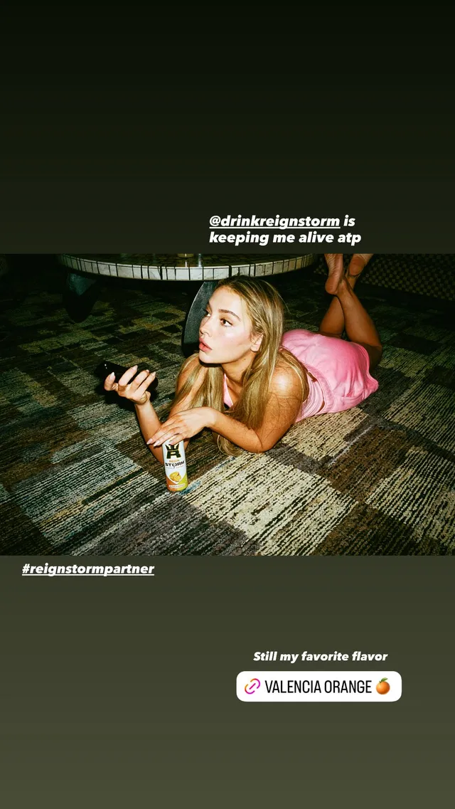 Madelyn Cline lying on a wooden floor with her bare feet raised.