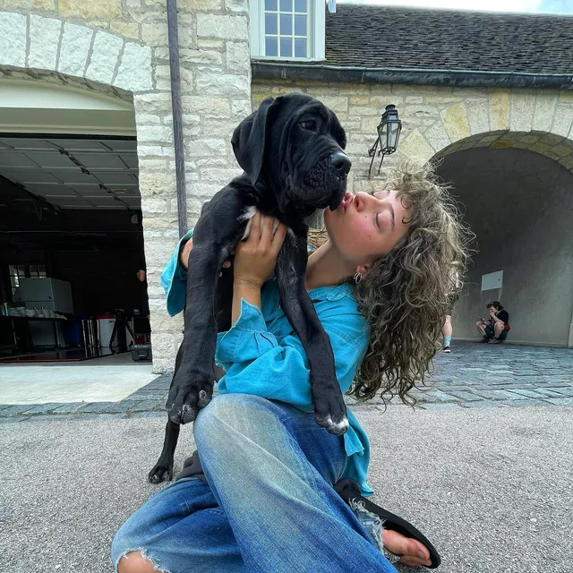 Odessa A'zion sitting in jeans while holding a dog.