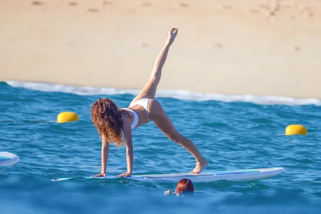 Sarah Hyland balancing on a paddleboard on the sea.