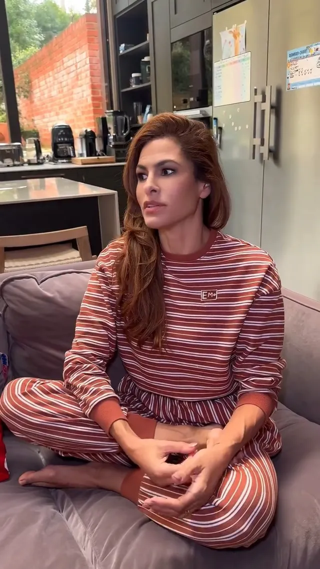 Eva Mendes sitting cross legged in striped loungewear.