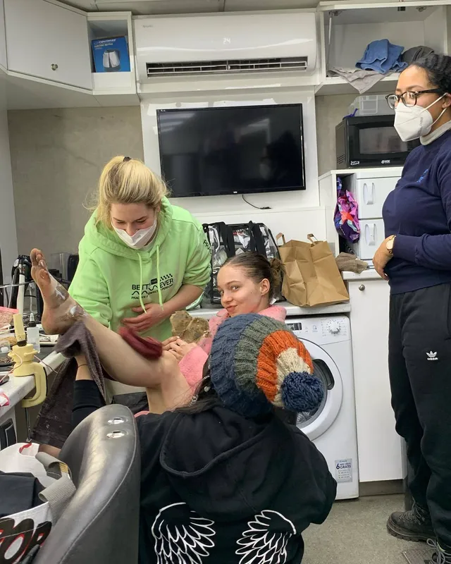 Emma Myers preparing barefoot for a scene beside crew members.