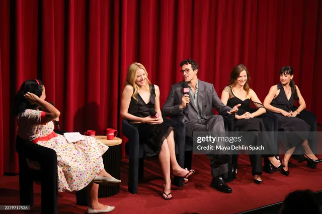Sarah Pidgeon sitting onstage in a black dress and heels during a panel.