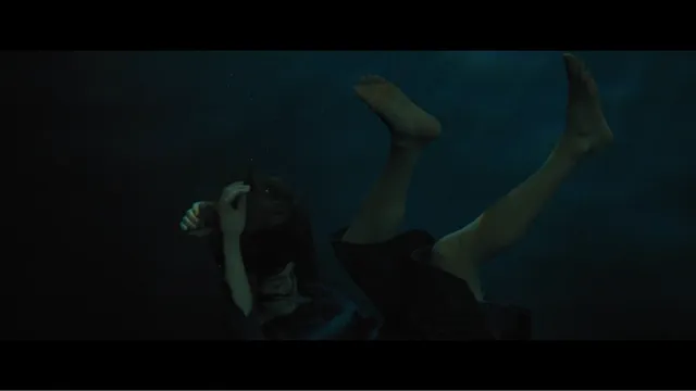 Grace Van Patten floating barefoot underwater in a film scene.