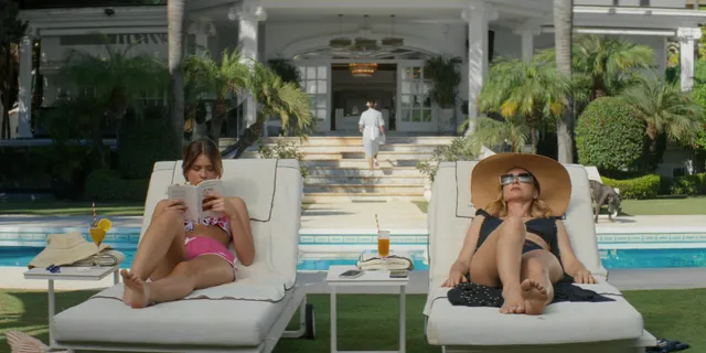 Nicole Wallace reclining barefoot beside a friend on a pool lounger in a scene.
