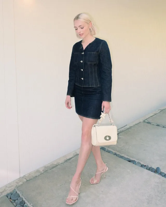 AnnaSophia Robb posing outdoors in a black outfit and flat sandals.
