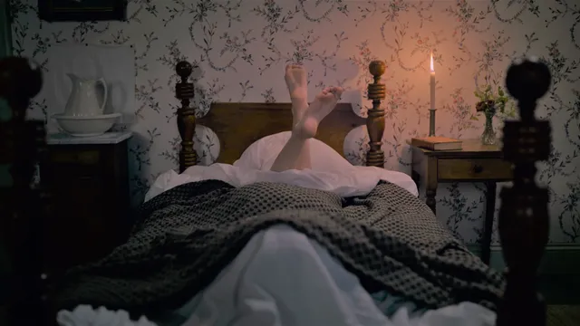 Hailee Steinfeld lying on a bed with bare feet raised.