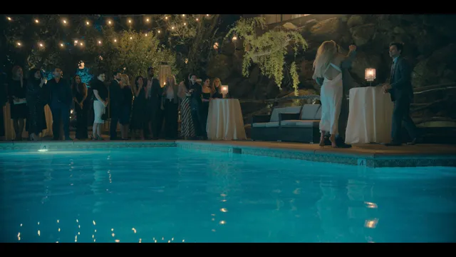 Kate Hudson standing beside a swimming pool at night in a scene.