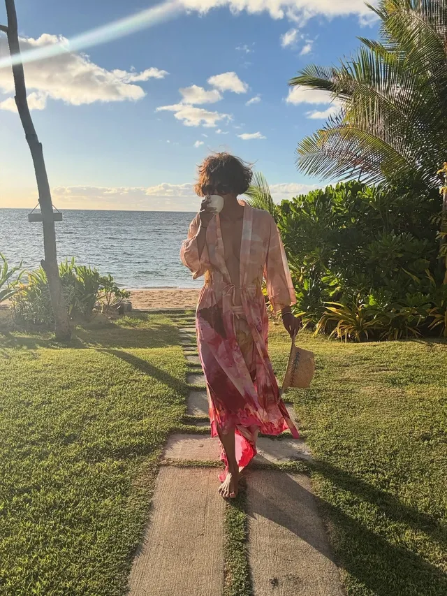 Halle Berry walking barefoot outside in a pink cover-up.