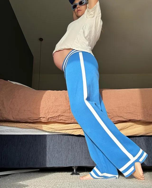Teresa Palmer posing indoors in blue trousers.