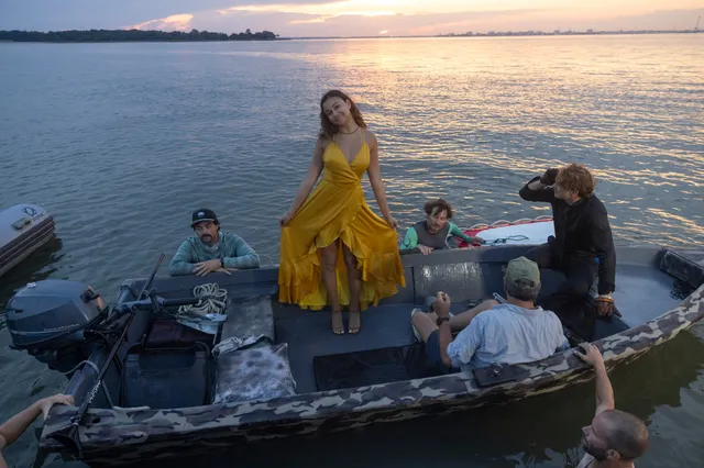 Madison Bailey standing barefoot on a boat in a yellow dress.