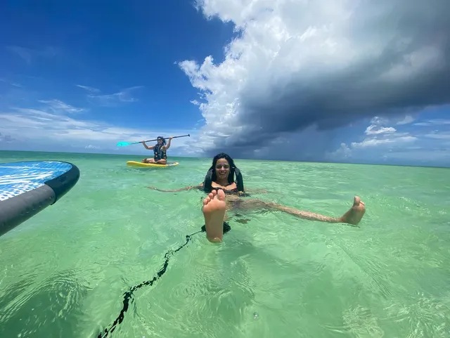 Camila Cabello relaxing in shallow seawater with bare feet raised.