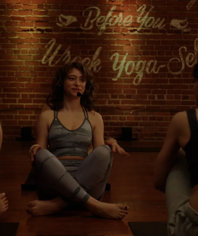 Odessa A'zion sitting barefoot cross-legged in a group scene.
