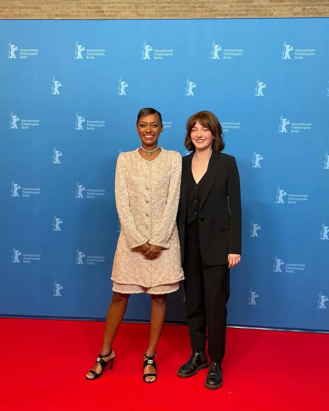Sophie Wilde standing beside another woman in a pale dress and black heels.