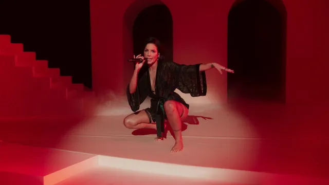 Halsey a black outfit and red heels against a red backdrop.