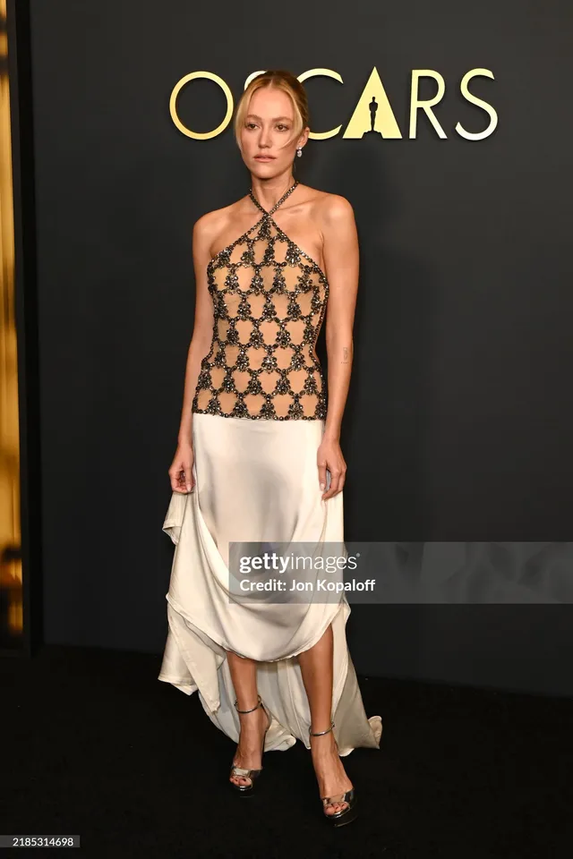 Maika Monroe wearing a patterned top and heels at an awards event.
