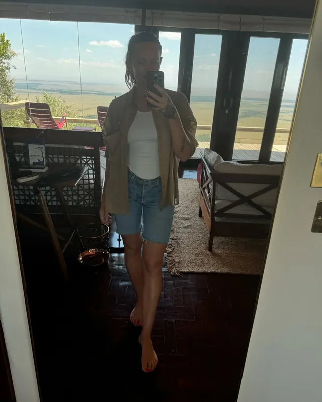 Tove Lo posing barefoot for a mirror photograph in a jacket and denim shorts.