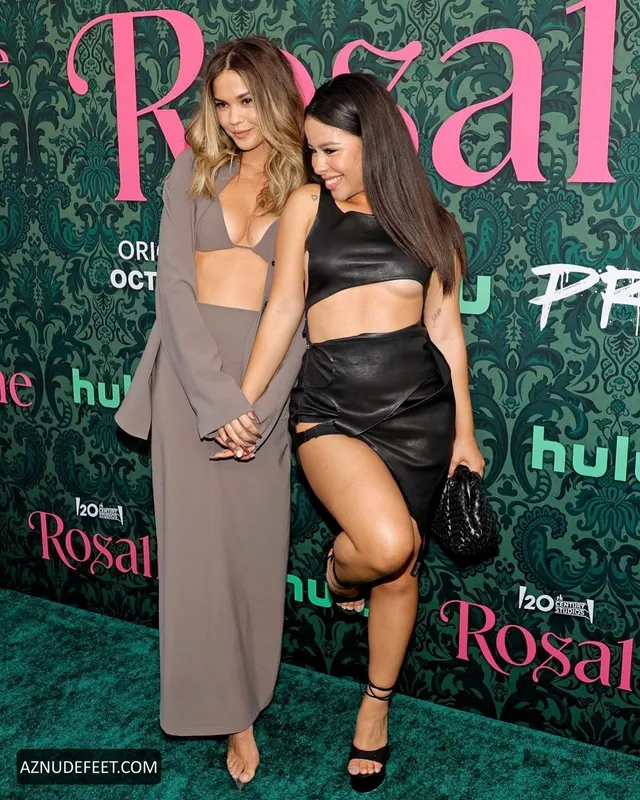 Cierra Ramirez in a black cutout dress and heeled sandals beside a friend at an event.