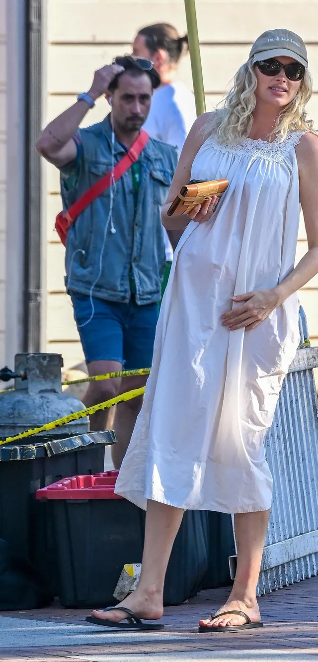 Elsa Hosk walking in flat sandals and a long white dress.
