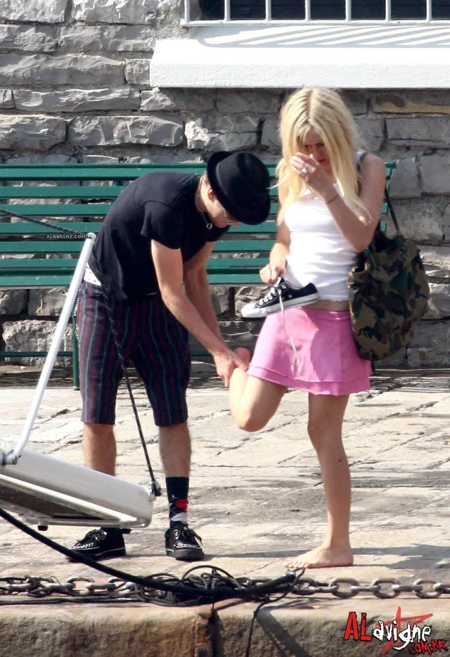 Avril Lavigne standing barefoot beside filming equipment outdoors.