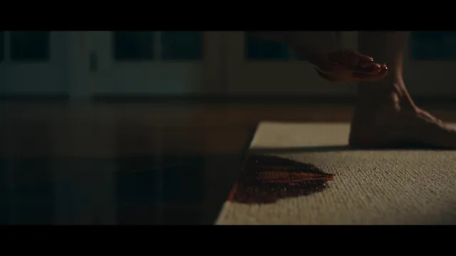 Jessica Biel barefoot beside a rug in a dimly lit screen scene.