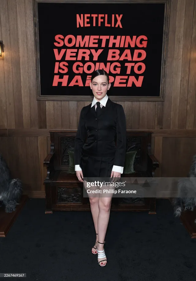 Victoria Pedretti posing at a Netflix event in a dark outfit.