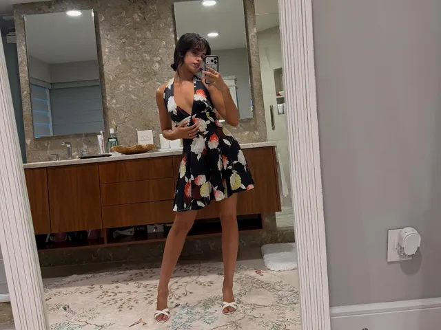 Camila Cabello taking a mirror photo in a floral dress and heels.