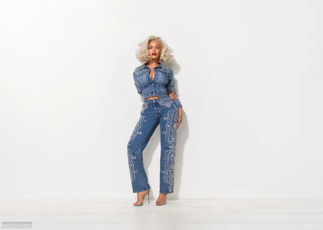 Beyoncé standing barefoot in a denim outfit against a white backdrop.