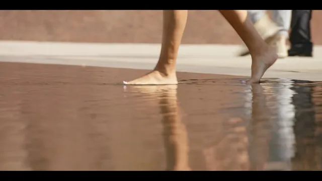 Samantha Logan shown walking barefoot on a wooden floor.