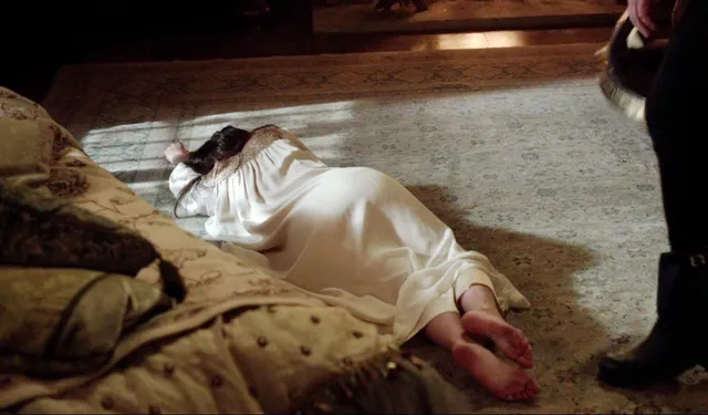 Adelaide Kane lying on a rug during a screen scene.