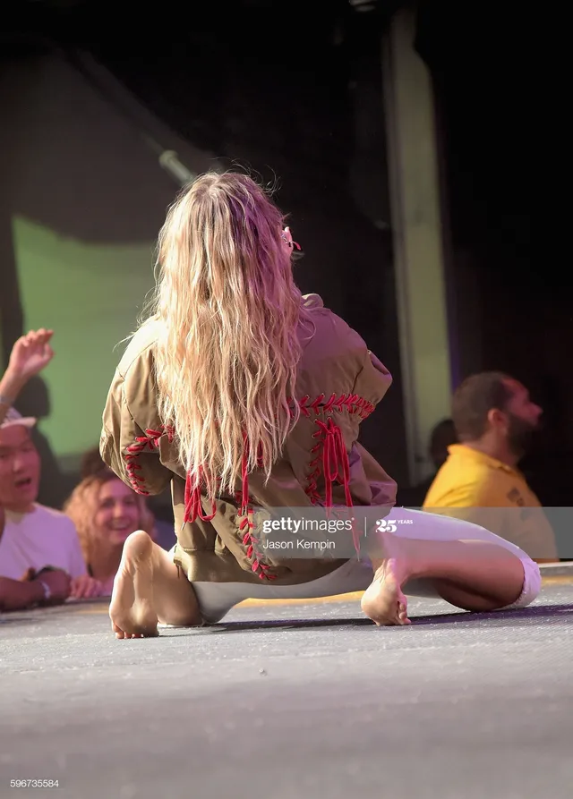 Tove Lo sitting on stage with bare soles visible.
