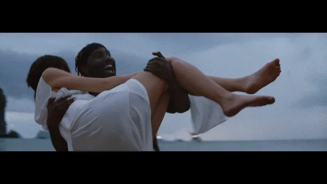 Gemma Chan being carried by a man in a screen scene.