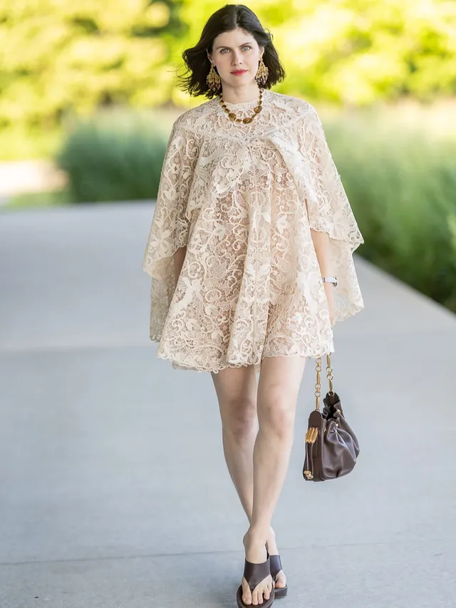 Alexandra Daddario wearing a pale patterned dress and black sandals.
