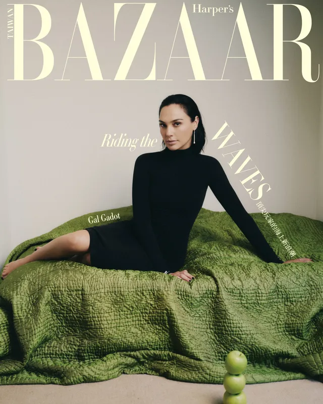 Gal Gadot reclining barefoot on a green sofa for a magazine portrait.