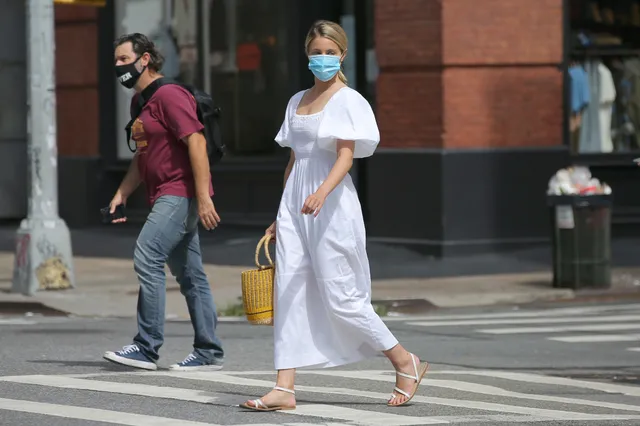 Dianna Agron crossing a street in a white dress and sandals.