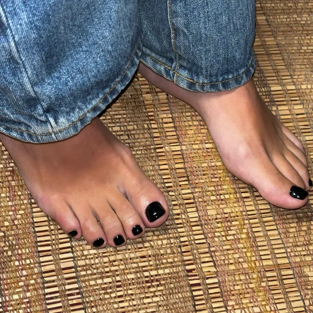 Lily Allen: close view of black-painted toenails on a woven mat.