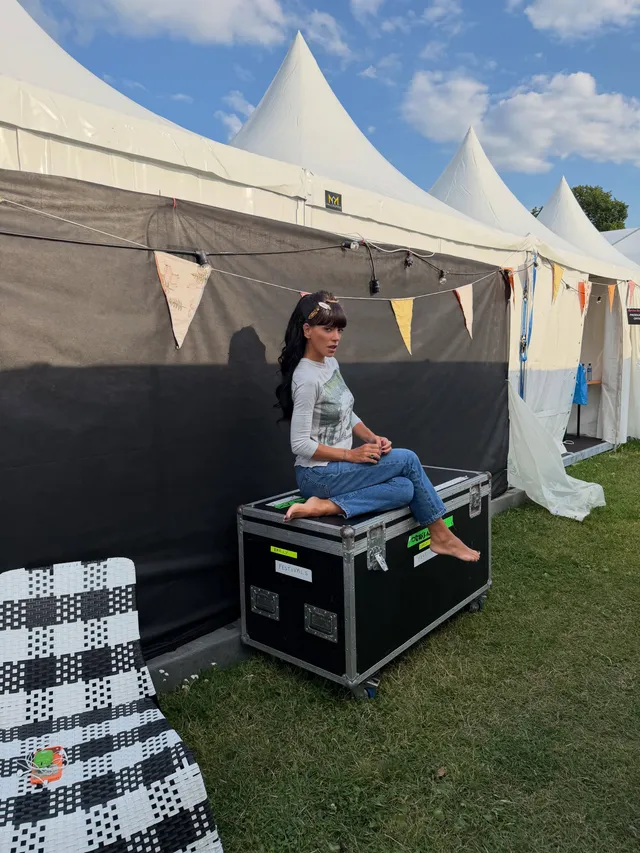 Lily Allen sitting on a case outdoors wearing colorful socks.