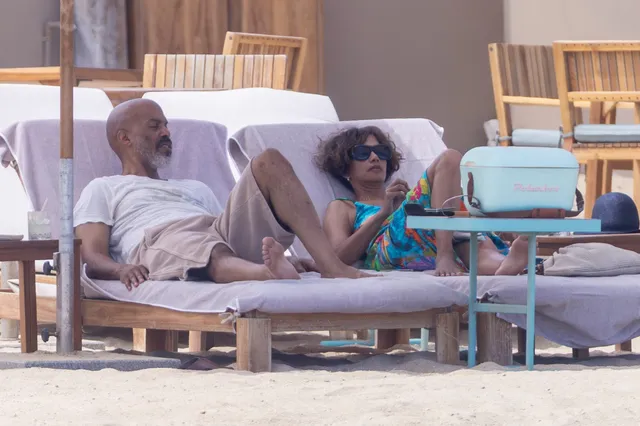 Halle Berry reclining barefoot on a lounger by the pool.