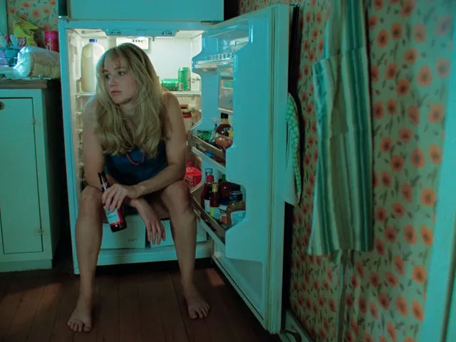 Jennifer Lawrence sitting barefoot in a kitchen screen scene.
