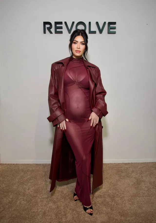 Megan Fox wearing a burgundy coat and heeled sandals at an event.