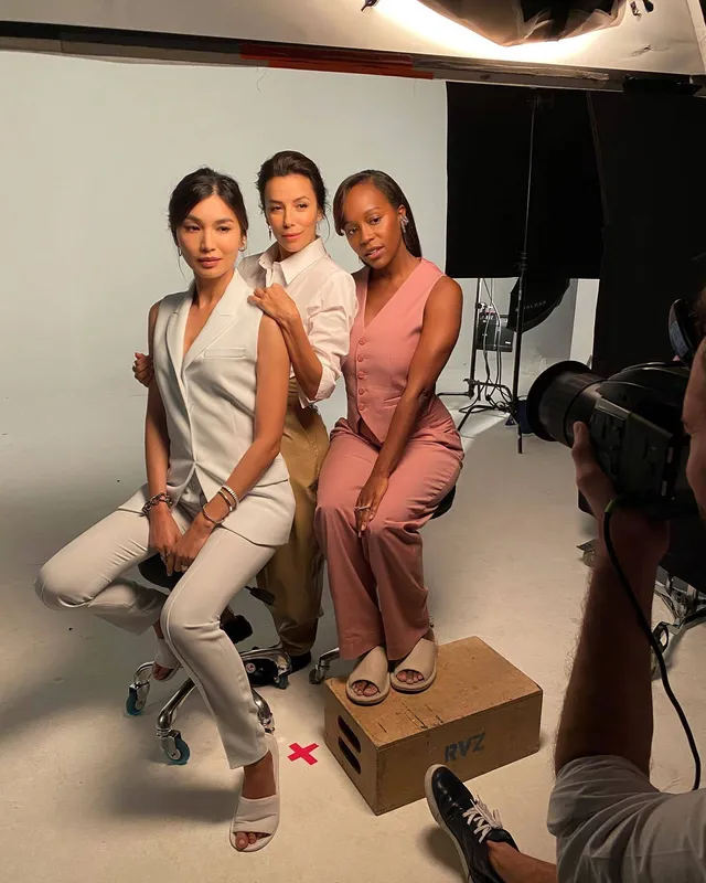 Gemma Chan sitting with other performers during a studio shoot.
