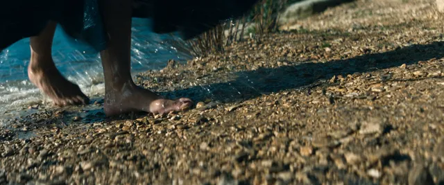 Tessa Thompson walking on stones near the water in a screen scene.