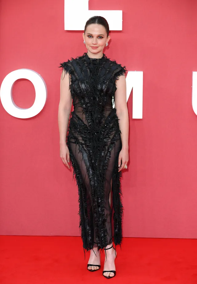 Cailee Spaeny wearing a black lace dress and black heels at a premiere.