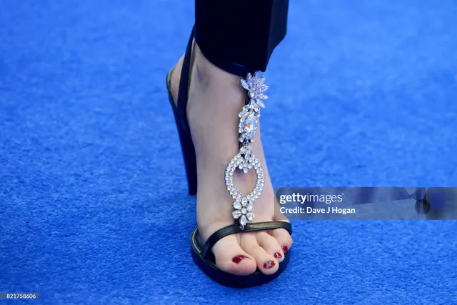 Cara Delevingne wearing black jewelled sandals on a blue carpet.